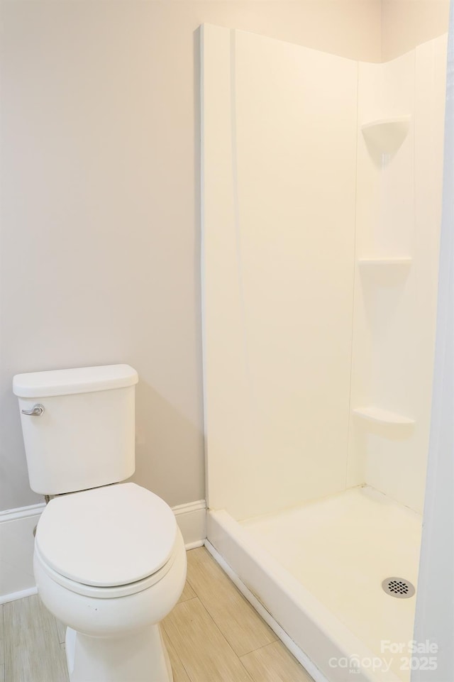 bathroom featuring hardwood / wood-style flooring, a shower, and toilet