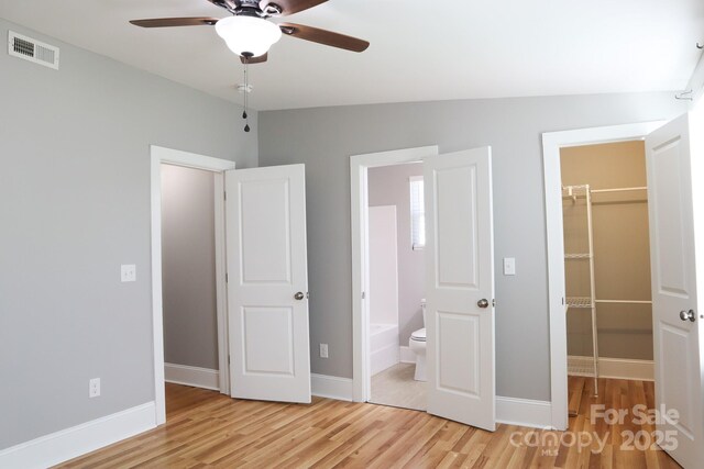 unfurnished bedroom featuring a walk in closet, ceiling fan, light hardwood / wood-style floors, and a closet