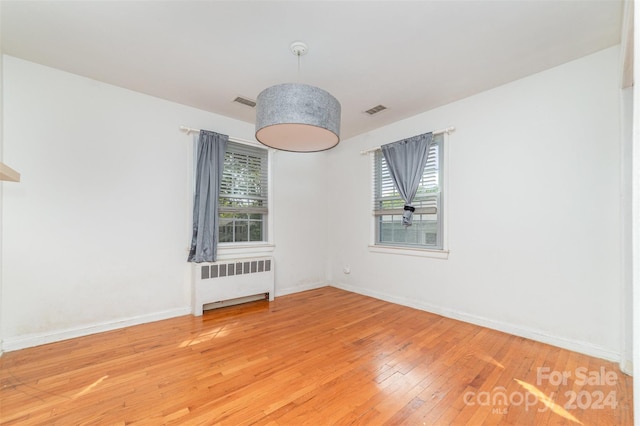 spare room featuring radiator heating unit and hardwood / wood-style floors