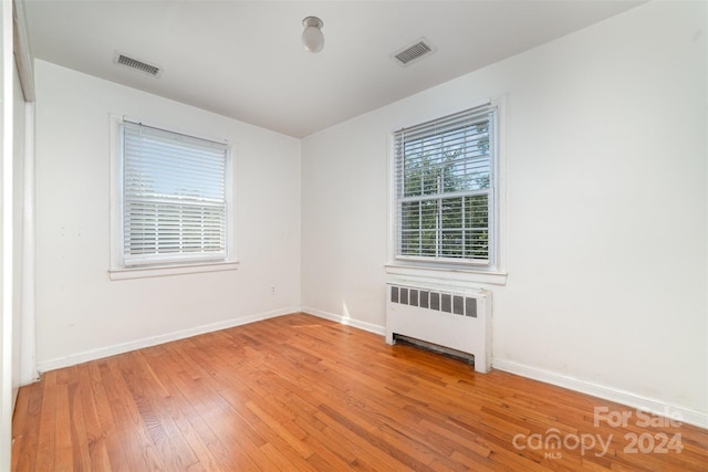 unfurnished room with radiator and wood-type flooring