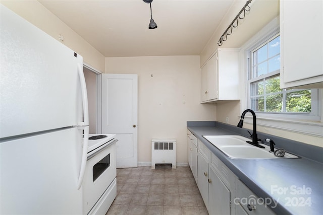 kitchen with white appliances, white cabinets, and radiator