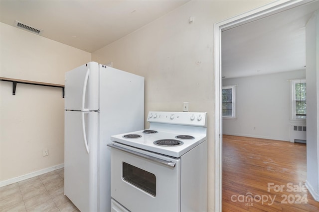 kitchen with radiator, light hardwood / wood-style floors, and white appliances