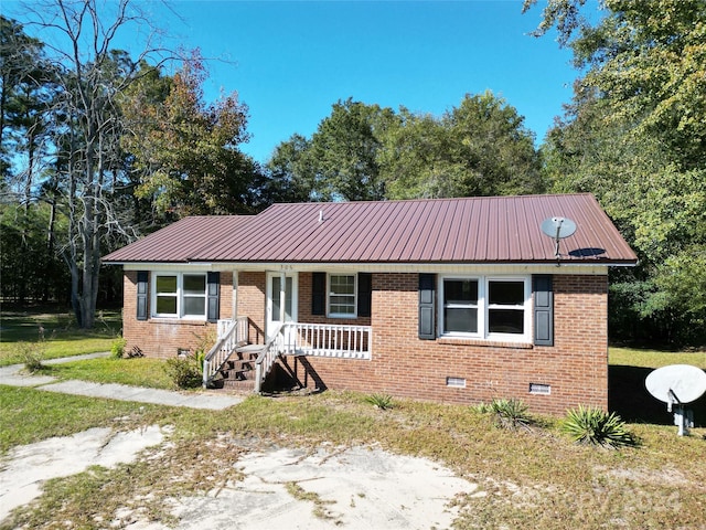 single story home featuring crawl space, brick siding, a porch, and metal roof