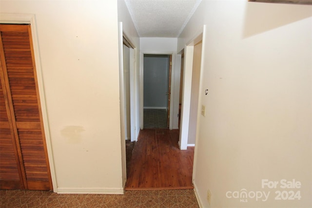 corridor featuring a textured ceiling and hardwood / wood-style floors