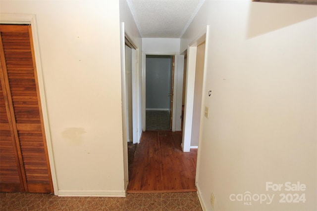 corridor with baseboards and a textured ceiling