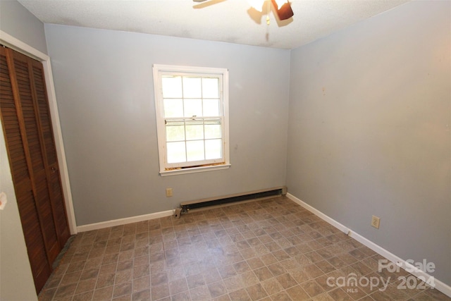 unfurnished bedroom featuring a closet, baseboard heating, and ceiling fan