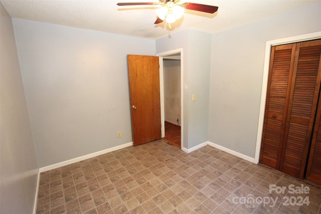 unfurnished bedroom featuring a closet, baseboards, tile patterned floors, and a ceiling fan