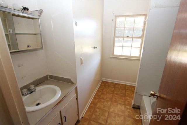 full bath featuring vanity, baseboards, and a tub to relax in