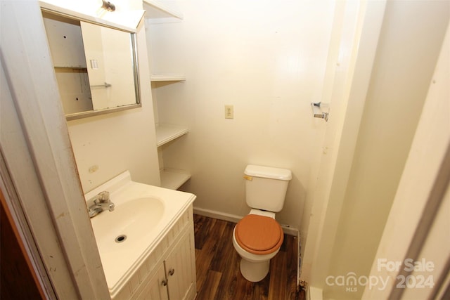 bathroom with wood finished floors, toilet, vanity, and baseboards