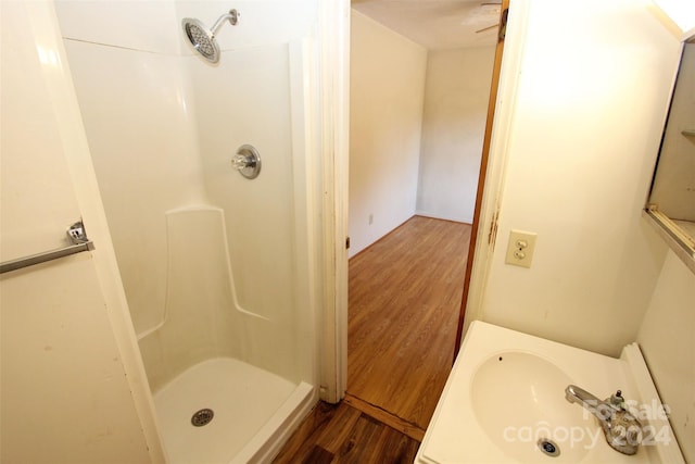 bathroom with hardwood / wood-style flooring, walk in shower, and sink