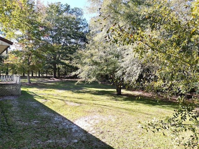 view of green lawn featuring a deck