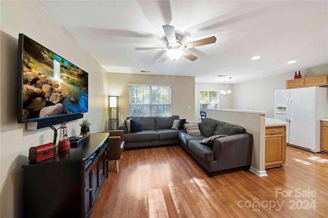 living room featuring ceiling fan with notable chandelier and light hardwood / wood-style flooring