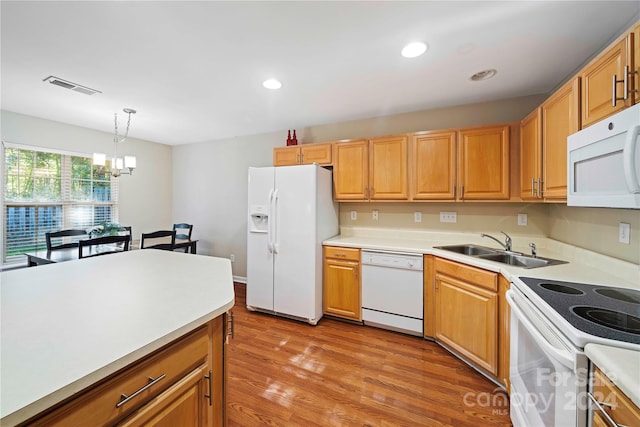 kitchen with light hardwood / wood-style floors, an inviting chandelier, white appliances, sink, and hanging light fixtures