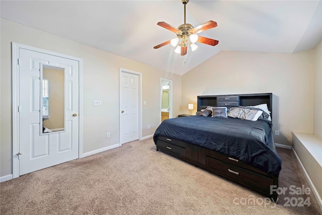 bedroom with ceiling fan, lofted ceiling, ensuite bathroom, and light carpet