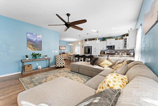 living room featuring ceiling fan with notable chandelier and hardwood / wood-style flooring