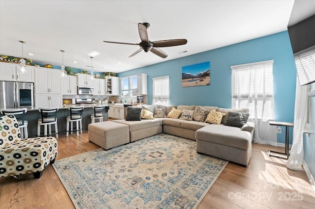 living room with ceiling fan and light hardwood / wood-style flooring