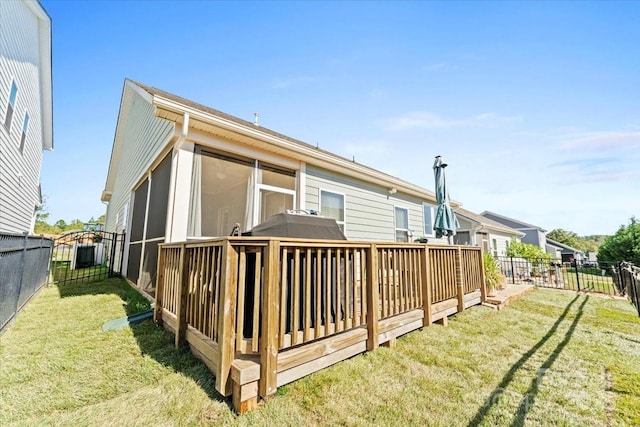 rear view of property featuring a deck, a sunroom, and a yard