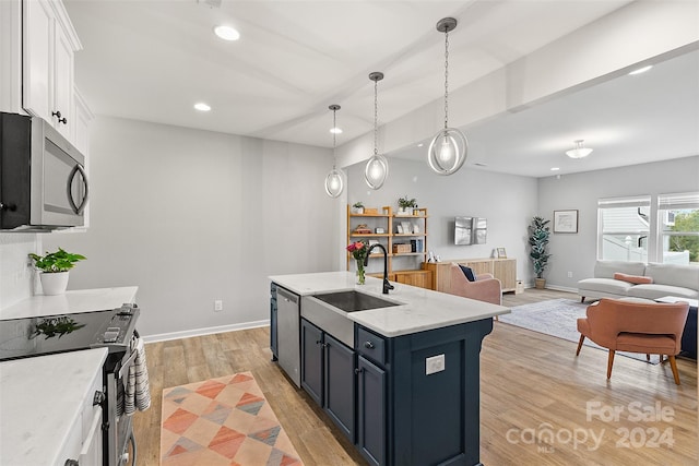 kitchen with white cabinets, hanging light fixtures, appliances with stainless steel finishes, light hardwood / wood-style floors, and sink