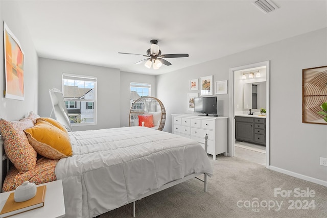 bedroom featuring light colored carpet, connected bathroom, sink, and ceiling fan