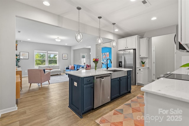 kitchen with decorative light fixtures, blue cabinets, white cabinetry, an island with sink, and stainless steel appliances