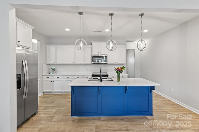 kitchen featuring hanging light fixtures, stainless steel appliances, and white cabinets