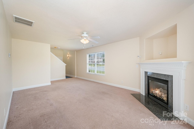 unfurnished living room featuring carpet flooring, a premium fireplace, and ceiling fan