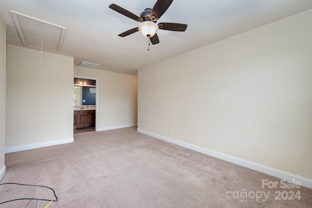 unfurnished bedroom featuring ceiling fan, light colored carpet, and ensuite bath