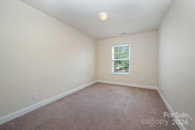 carpeted spare room featuring baseboards and visible vents