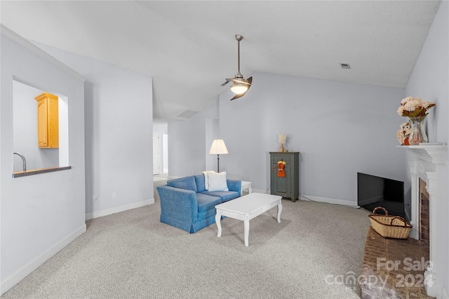 carpeted living room featuring ceiling fan, vaulted ceiling, and a brick fireplace