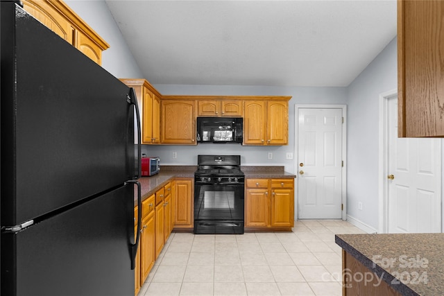 kitchen with lofted ceiling, black appliances, and light tile patterned floors