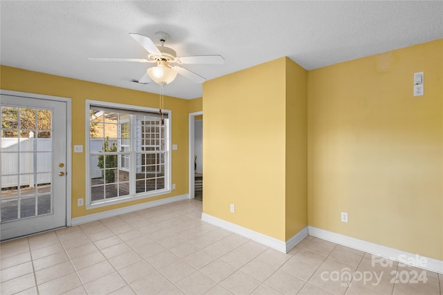 tiled empty room featuring ceiling fan and a textured ceiling