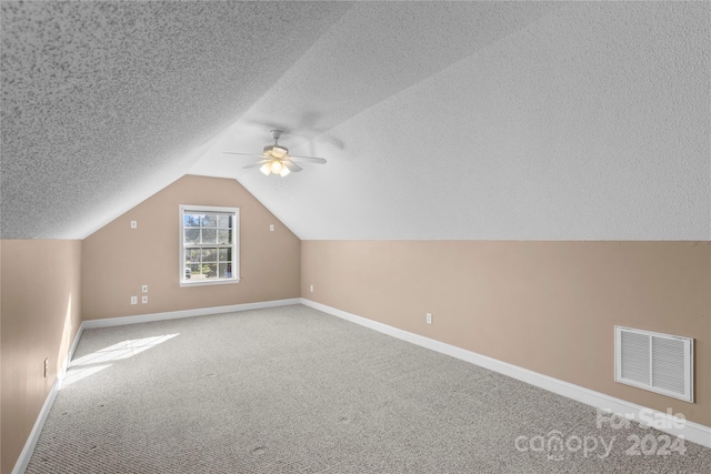 additional living space featuring a textured ceiling, ceiling fan, carpet, and vaulted ceiling