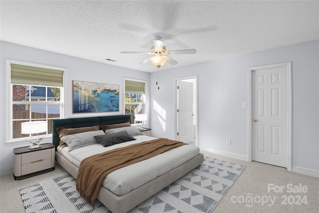 bedroom with light carpet, a textured ceiling, and ceiling fan