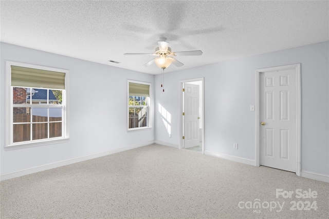 carpeted empty room featuring ceiling fan and a textured ceiling