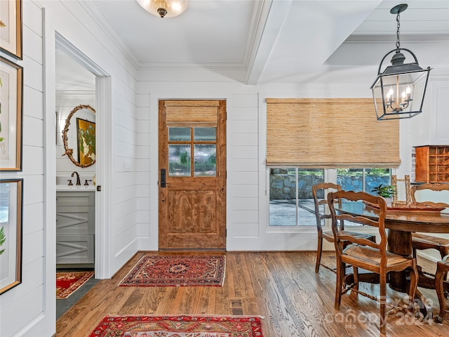 entrance foyer featuring an inviting chandelier, dark hardwood / wood-style floors, ornamental molding, and sink