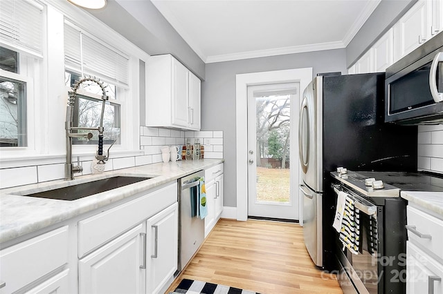 kitchen featuring white cabinets, a wealth of natural light, backsplash, and appliances with stainless steel finishes