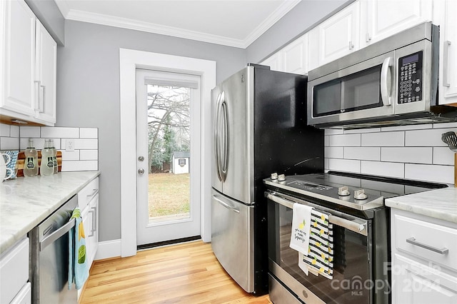 kitchen featuring appliances with stainless steel finishes, light hardwood / wood-style floors, decorative backsplash, white cabinets, and ornamental molding