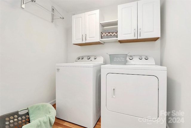 clothes washing area featuring cabinets, independent washer and dryer, and light hardwood / wood-style flooring