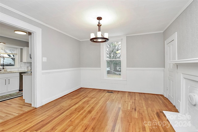 unfurnished dining area with crown molding, light hardwood / wood-style flooring, a notable chandelier, and sink