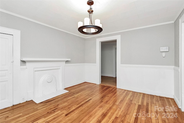 unfurnished dining area featuring a notable chandelier, light wood-type flooring, and ornamental molding