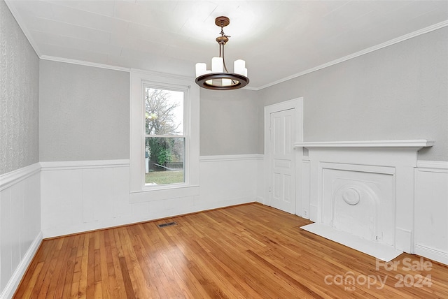 unfurnished dining area with a notable chandelier, wood-type flooring, and crown molding