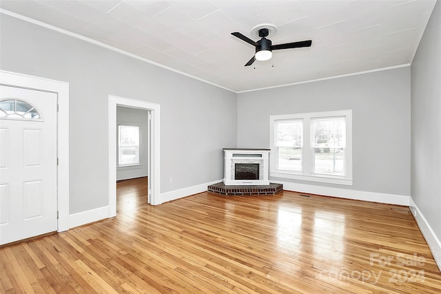 unfurnished living room with hardwood / wood-style flooring, ceiling fan, ornamental molding, and a brick fireplace