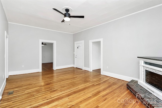 unfurnished living room with hardwood / wood-style flooring, ceiling fan, ornamental molding, and a brick fireplace