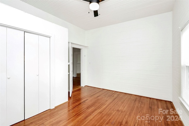 unfurnished bedroom featuring a closet, light hardwood / wood-style flooring, and ceiling fan