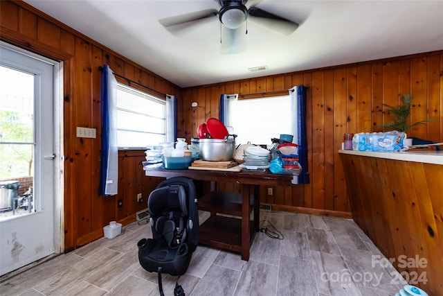 office area featuring ceiling fan, wooden walls, and light hardwood / wood-style floors