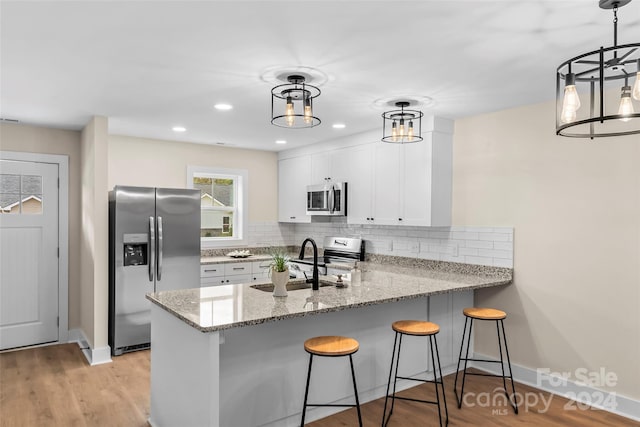 kitchen with decorative light fixtures, stainless steel appliances, and kitchen peninsula