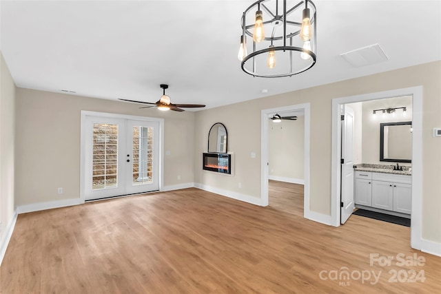 unfurnished living room featuring french doors, a notable chandelier, light hardwood / wood-style flooring, and sink