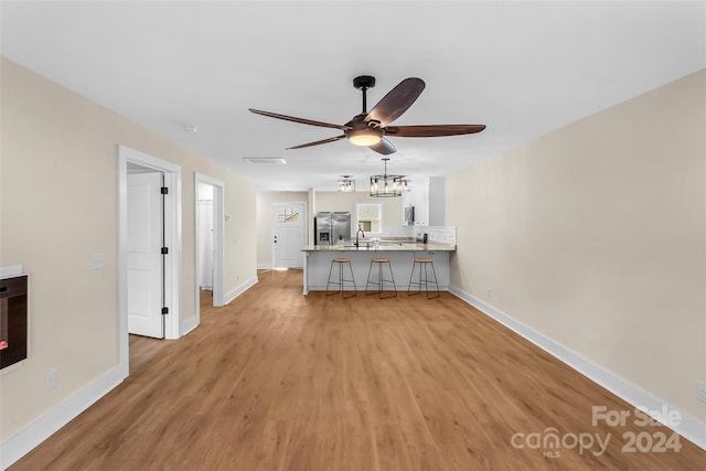 kitchen featuring a kitchen bar, stainless steel appliances, kitchen peninsula, and light hardwood / wood-style flooring