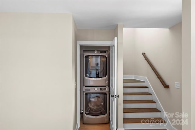 laundry area with wood-type flooring and stacked washing maching and dryer