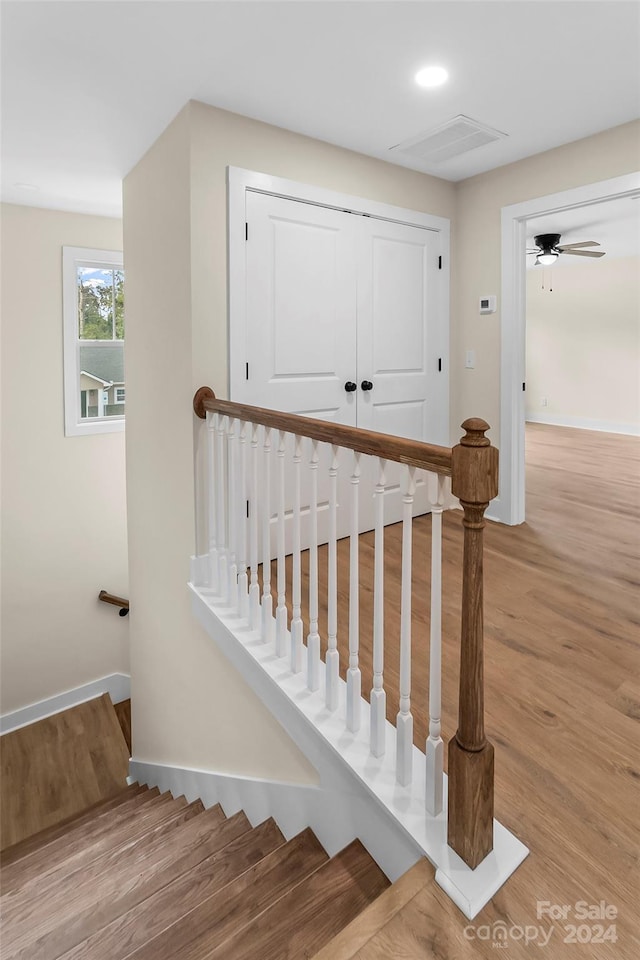 staircase with hardwood / wood-style floors and ceiling fan